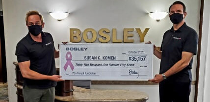 People holding breast cancer donation check from Bosley