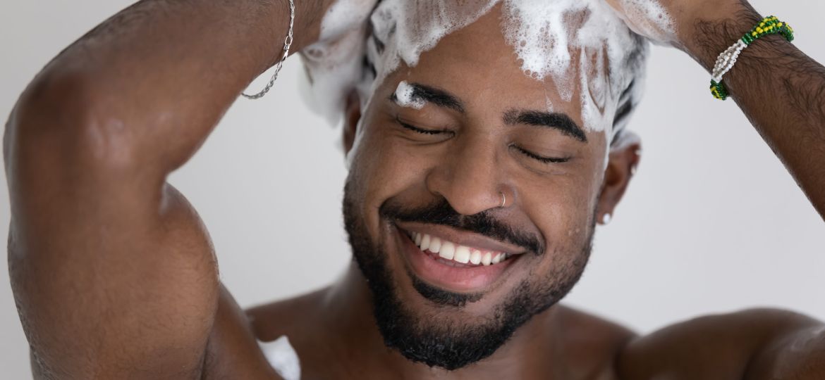 Close up smiling African American man washing hair with shampoo