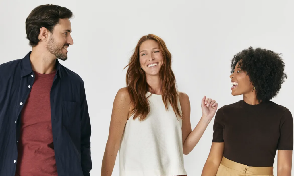 How Modern Hair Systems Work - a man and two women with HairClub hair systems casually stand in a row, look at each other, smile, and have fun together.