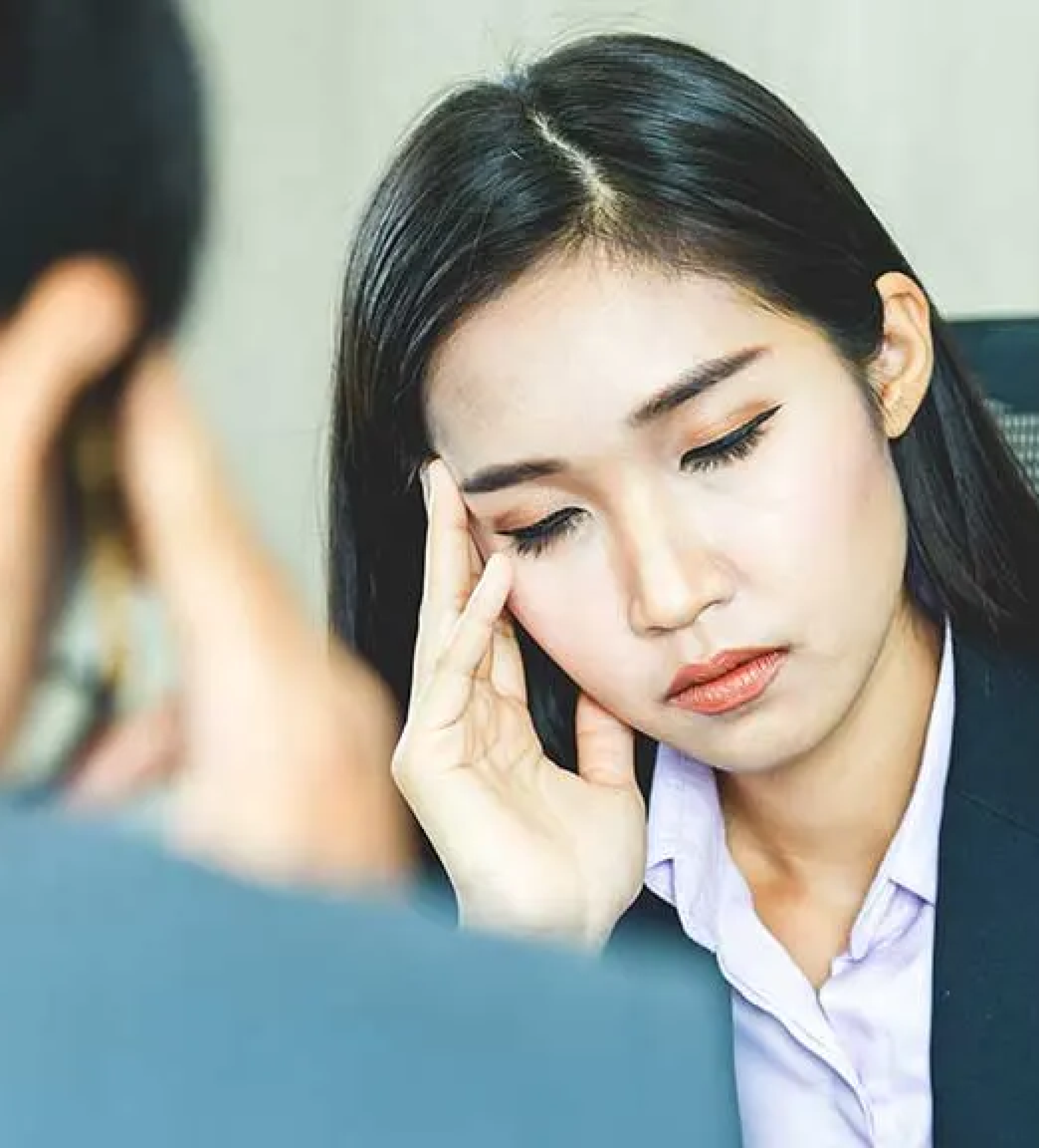 Can Stress Make Your Hair Fall Out - two business people sitting face to face, each looking down with their fingers on their temple, looking and stressed out and tired.