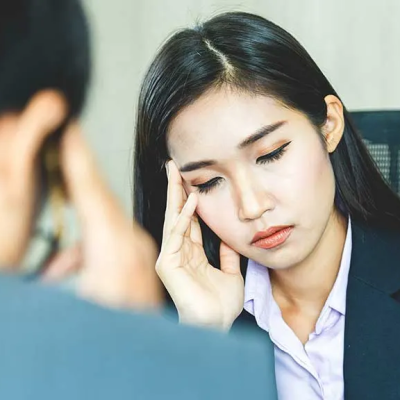 Can Stress Make Your Hair Fall Out - two business people sitting face to face, each looking down with their fingers on their temple, looking and stressed out and tired.