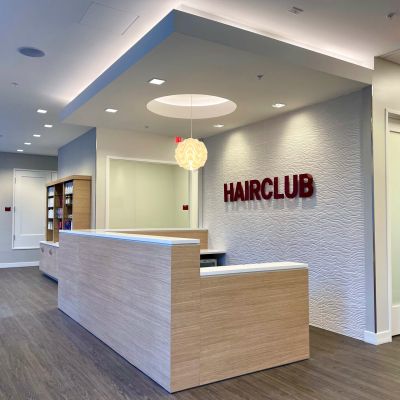 HairClub Place - the peaceful reception area of a HairClub Center - the HairClub logo is on the wall behind the reception desk.
