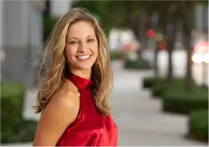 HairClub - Xtrands - Same Day Results - a woman with long blonde hair stands on a city sidewalk wearing a red blouse.