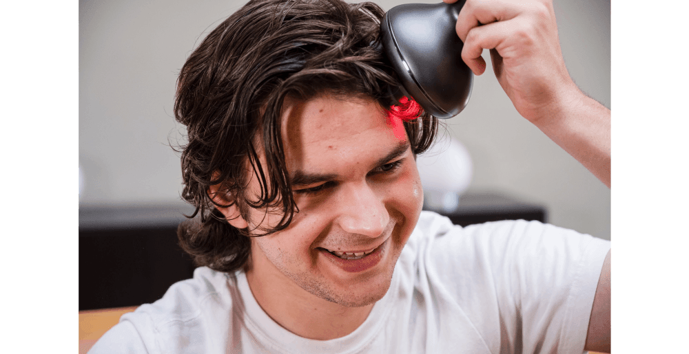Man using a handheld laser device on his scalp as part of Laser Therapy for Hair Loss, demonstrating low-level light treatment to stimulate hair growth and improve follicle health.