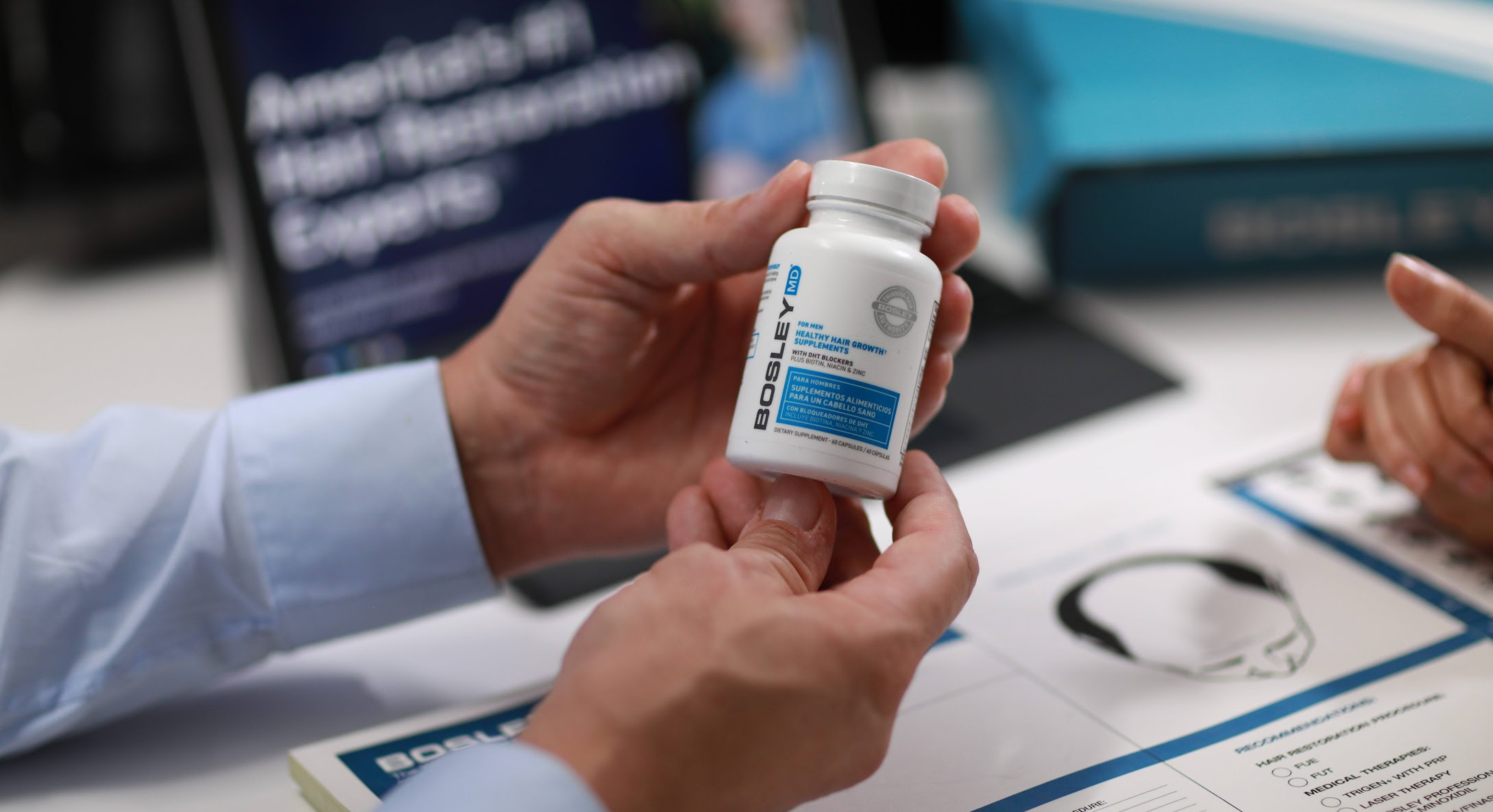 Bosley hair specialist holding DHT blocker supplement bottle during hair loss consultation