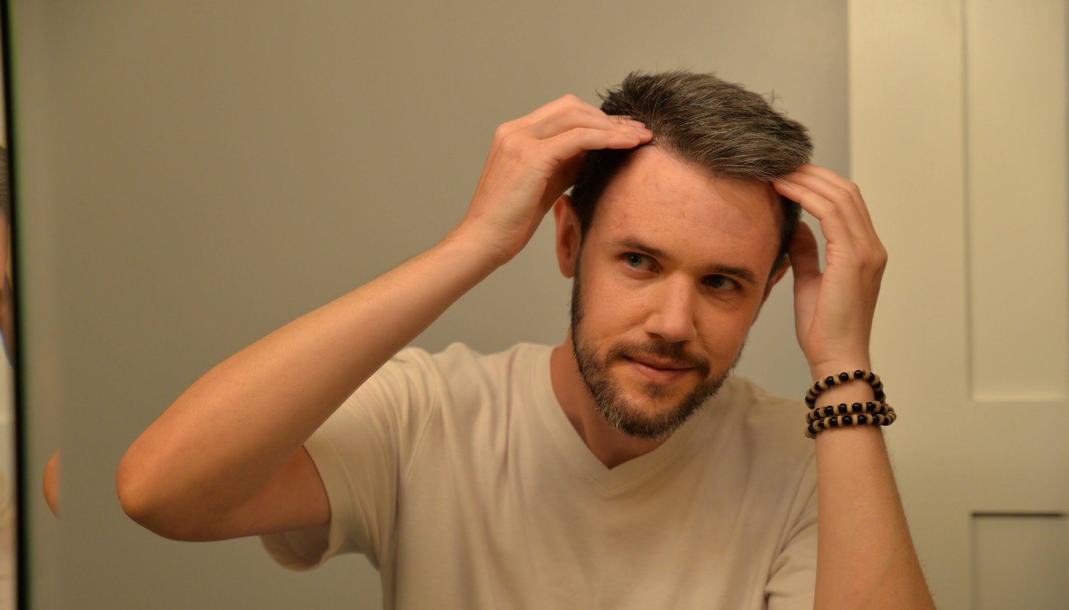 Man examining hair loss in mirror before seeking Hair Fall Treatment Near Me consultation